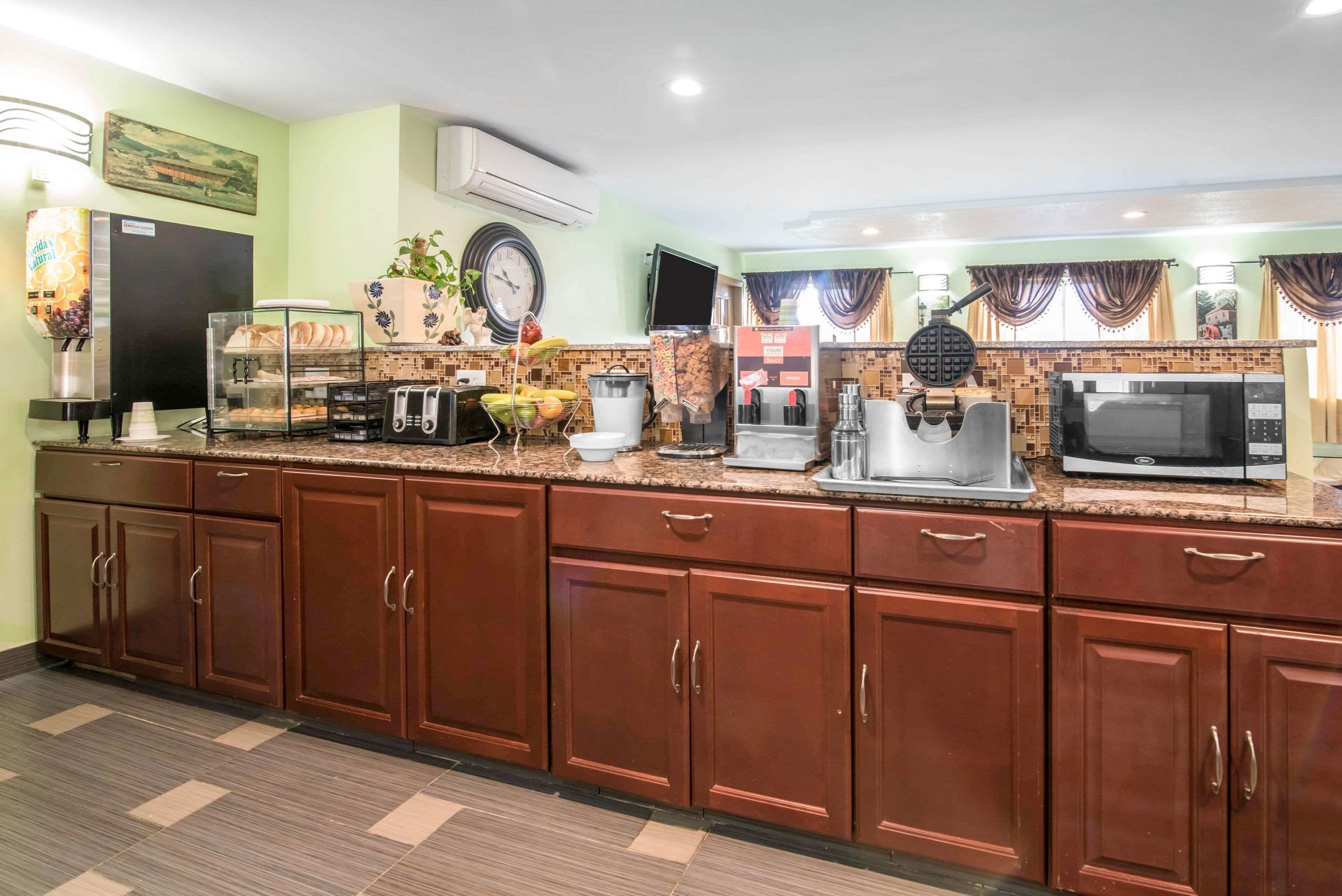 A hotel kitchen with a granite countertop, stainless steel appliances, and wooden cabinets.