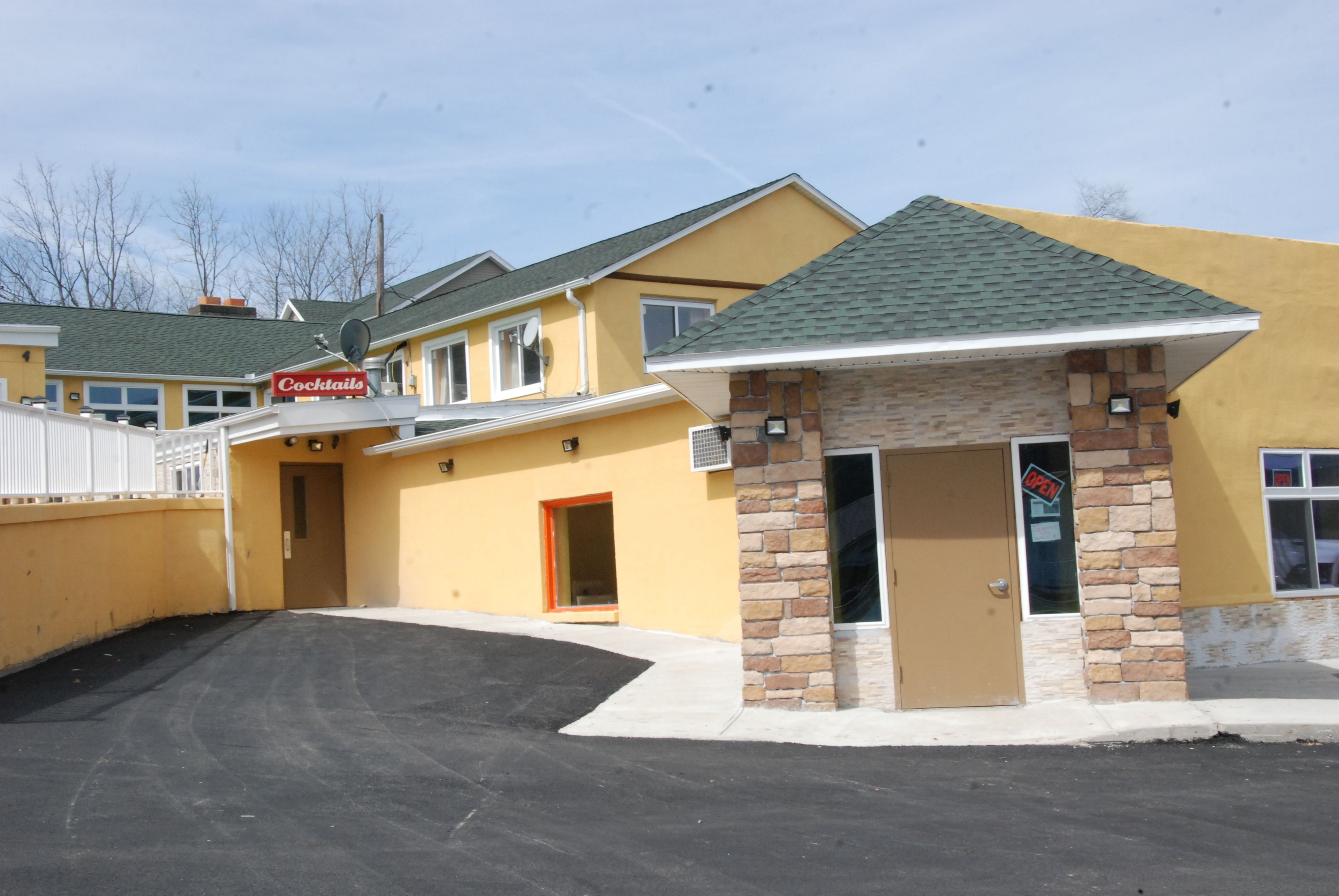 A yellow building with a 'Cocktails' sign, a stone entrance, and a 'UP!' sign on the door.