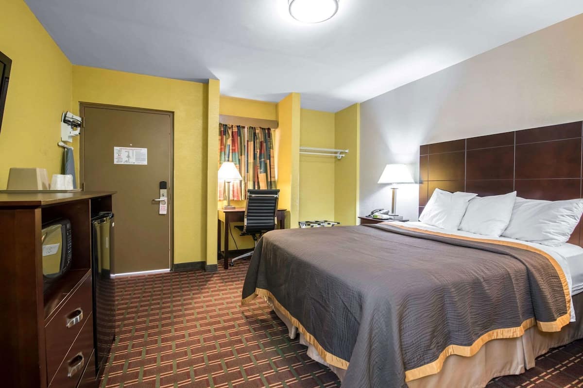 Habitación de hotel con cama, escritorio y una pequeña zona de estar.