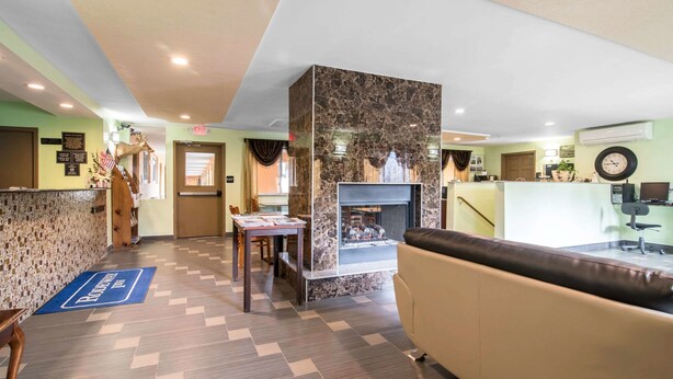 A hotel lobby with a reception desk, a fireplace, a seating area, and a herringbone-patterned floor.