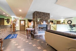 A hotel lobby with a reception desk, a fireplace, a seating area, and a herringbone-patterned floor.