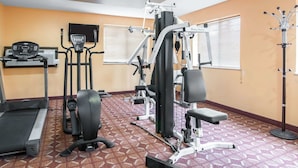 A gym with a treadmill, elliptical, and weight machines.
