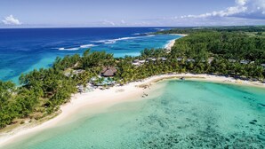 An aerial view of a tropical resort with a beachfront, clear turquoise waters, and dense palm trees. - Shandrani Beachcomber Resort & Spa (Blue Bay)
