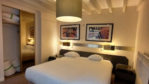 Een hotelkamer met een groot bed, een kledingkast, een nachtkastje en een lamp.
