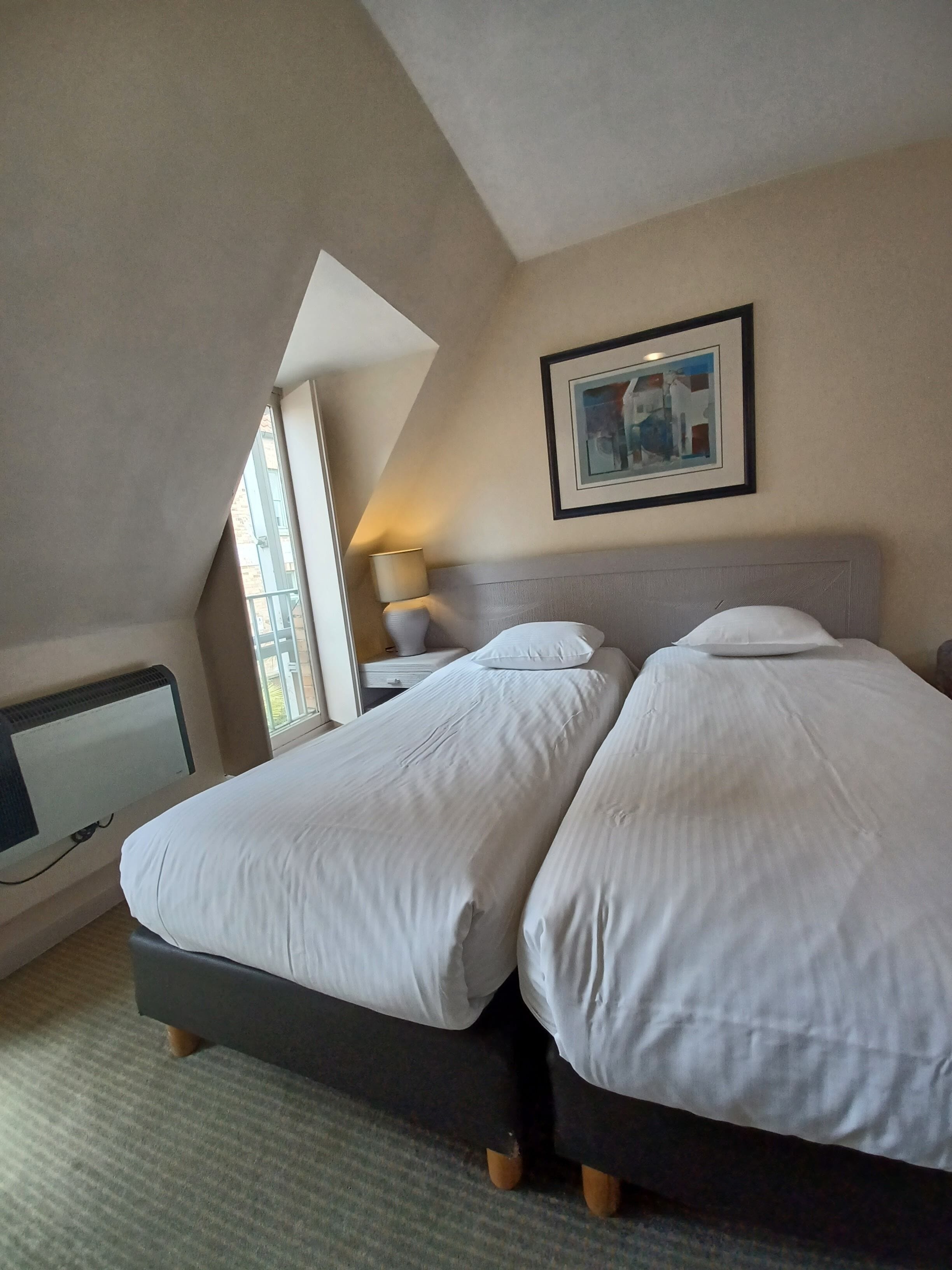 Une chambre d’hôtel avec deux lits, un bureau et une fenêtre.