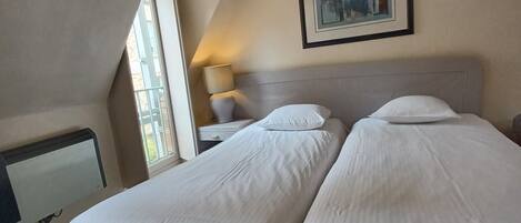 Une chambre d’hôtel avec deux lits, un bureau et une fenêtre.