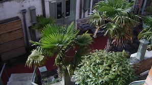 Een binnentuin met plantenpotten, een houten bankje en een tuinhuisje.