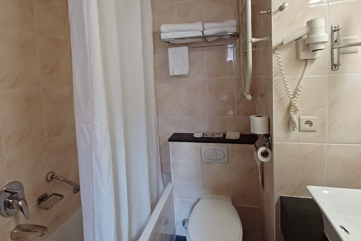 Une salle de bain avec une baignoire, des toilettes et un rideau de douche.