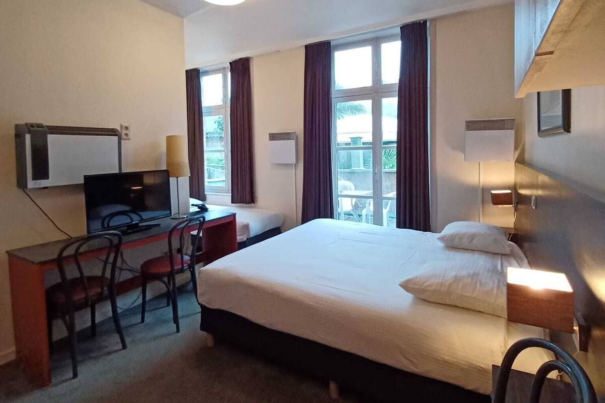 Une chambre d’hôtel avec un lit, un bureau, une télévision et des chaises.