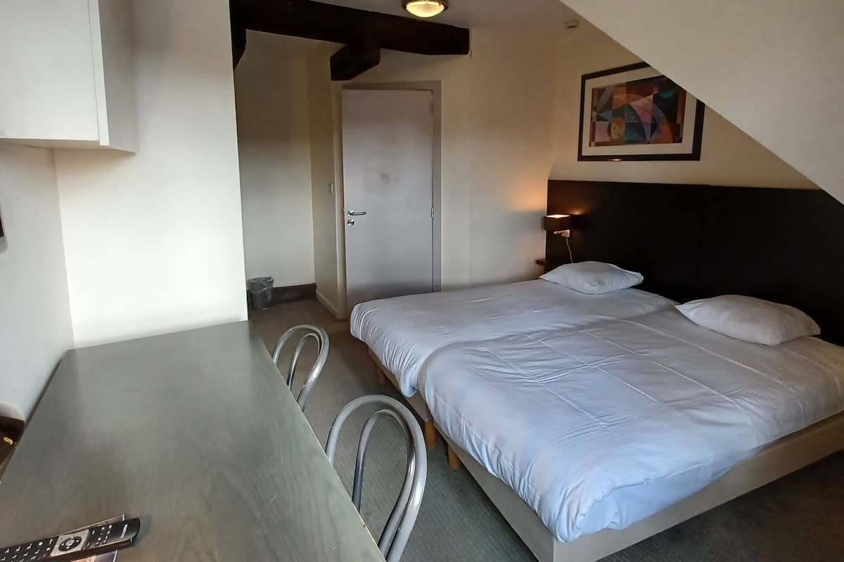 Une chambre d’hôtel avec un lit, un bureau et une chaise.
