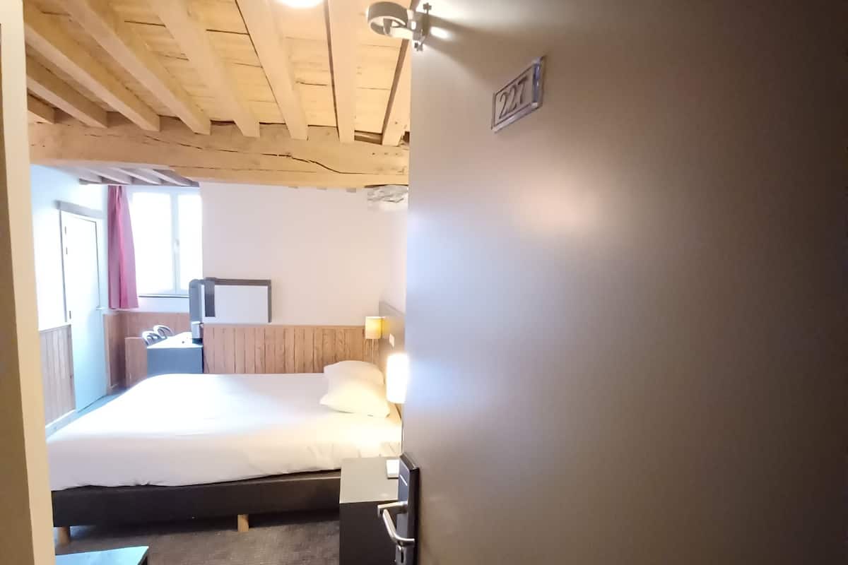 Une chambre d’hôtel avec un lit, une table de chevet, une lampe et une vue sur l’extérieur.