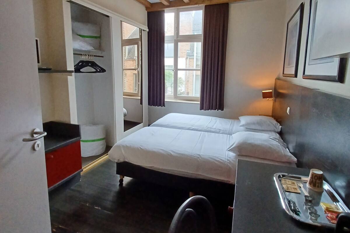 Une chambre avec un plafond en bois, un lit, un bureau avec un plateau et une chaise.