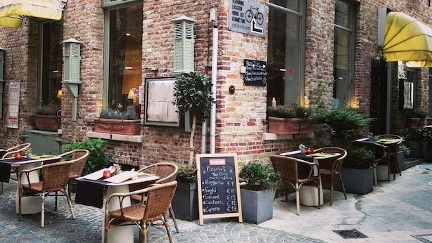 Een terras met bakstenen muren, rieten stoelen en een krijtbordmenu.