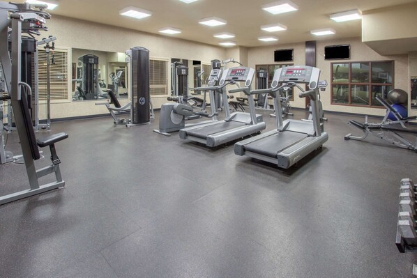 Un gimnasio con cintas de correr, máquinas de pesas y pelotas de ejercicio.