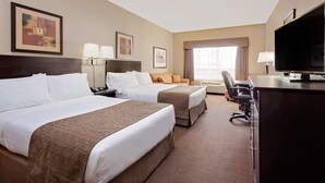 A hotel room with two beds, a desk, a TV, and a window with curtains. - Ramada by Wyndham Camrose (Camrose)