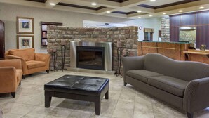 A lobby with a stone fireplace, leather sofas, and a reception desk. - Ramada by Wyndham Camrose (Camrose)