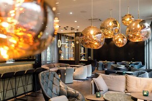 A modern lounge area with leather sofas, round tables, and hanging spherical light fixtures. - Motel One Nürnberg-Plärrer (Nuremberg)
