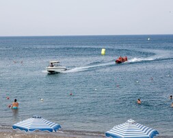 Escena de playa con un bote y gente en el agua.