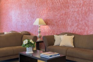 A living room with two sofas, a coffee table with a book, a lamp, and a vase with flowers.