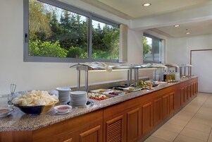 Disposición de buffet con distintos alimentos y vistas a zonas verdes al exterior.