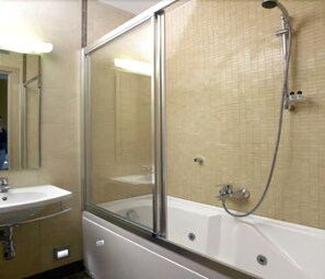 Un baño con ducha compartimentada con vidrio, un lavamanos y un espejo.
