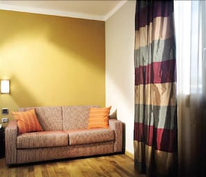 A living room with a sofa, a patterned curtain, and a wall-mounted light fixture. - Hotel Dei Vicari (Scarperia e San Piero)