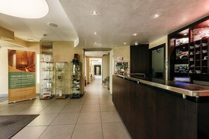 Un espace d’accueil d’hôtel comprenant un comptoir de réception, des vitrines et une affiche accrochée au mur.