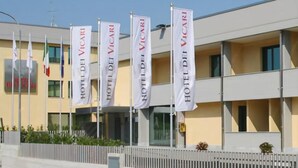 A hotel building with multiple flags, a modern facade, and a balcony. - Hotel Dei Vicari (Scarperia e San Piero)