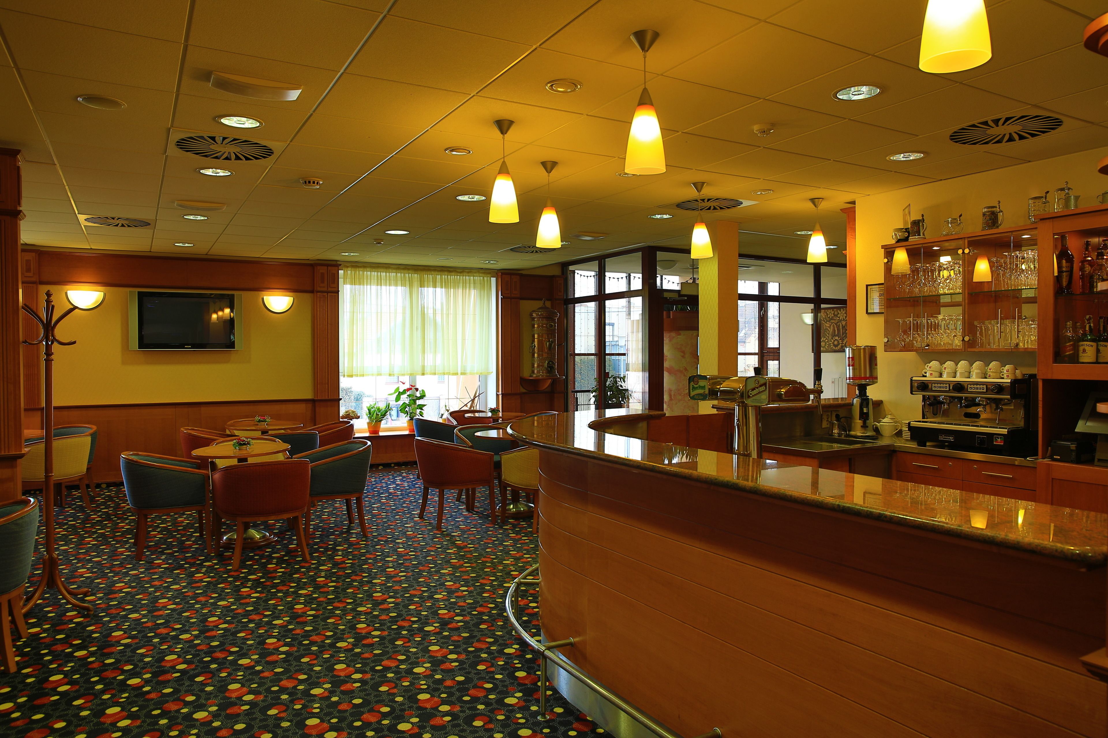 A hotel lobby with a bar area, seating, and a patterned carpet.