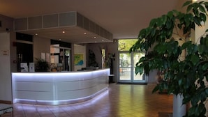 A reception area with a curved counter, a large window, and indoor plants. - Best Western Le Clos de l'Aube Rouge (Castelnau-le-Lez)