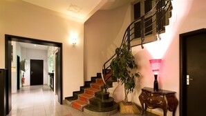 A staircase with a wooden handrail, a potted plant, and a table lamp. - Hôtel Esplanade (Strasbourg)