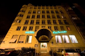 Un hotel con un llamativo letrero que dice 'HOTEL' y un letrero que dice 'Esplanade', con múltiples ventanas y una entrada central.