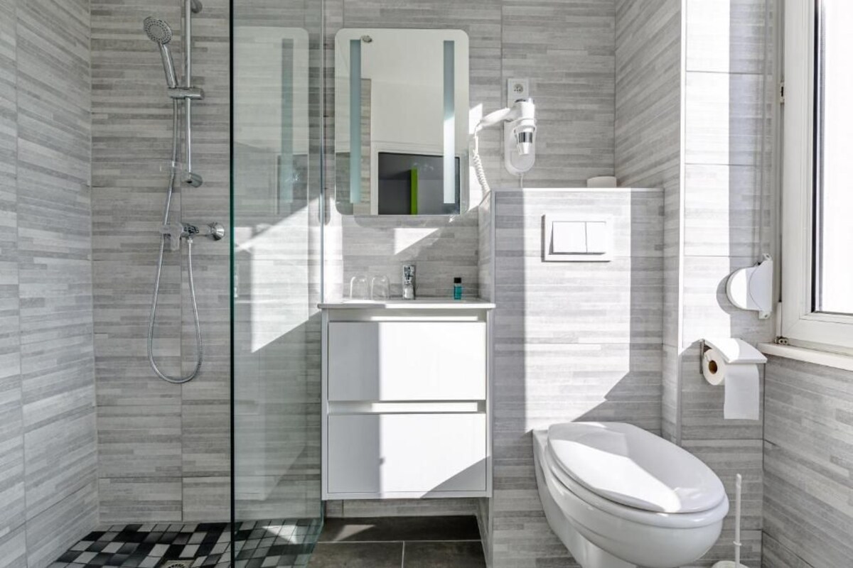 A modern bathroom with a glass shower enclosure, a white sink, and a toilet.