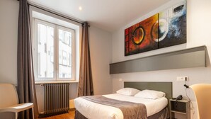 A modern hotel room with a large bed, a desk, a chair, and a window with curtains. - Hôtel Esplanade (Strasbourg)