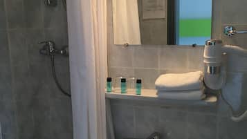 Ein Badezimmer mit Dusche, Waschbecken, Spiegel und Handtuchhalter.