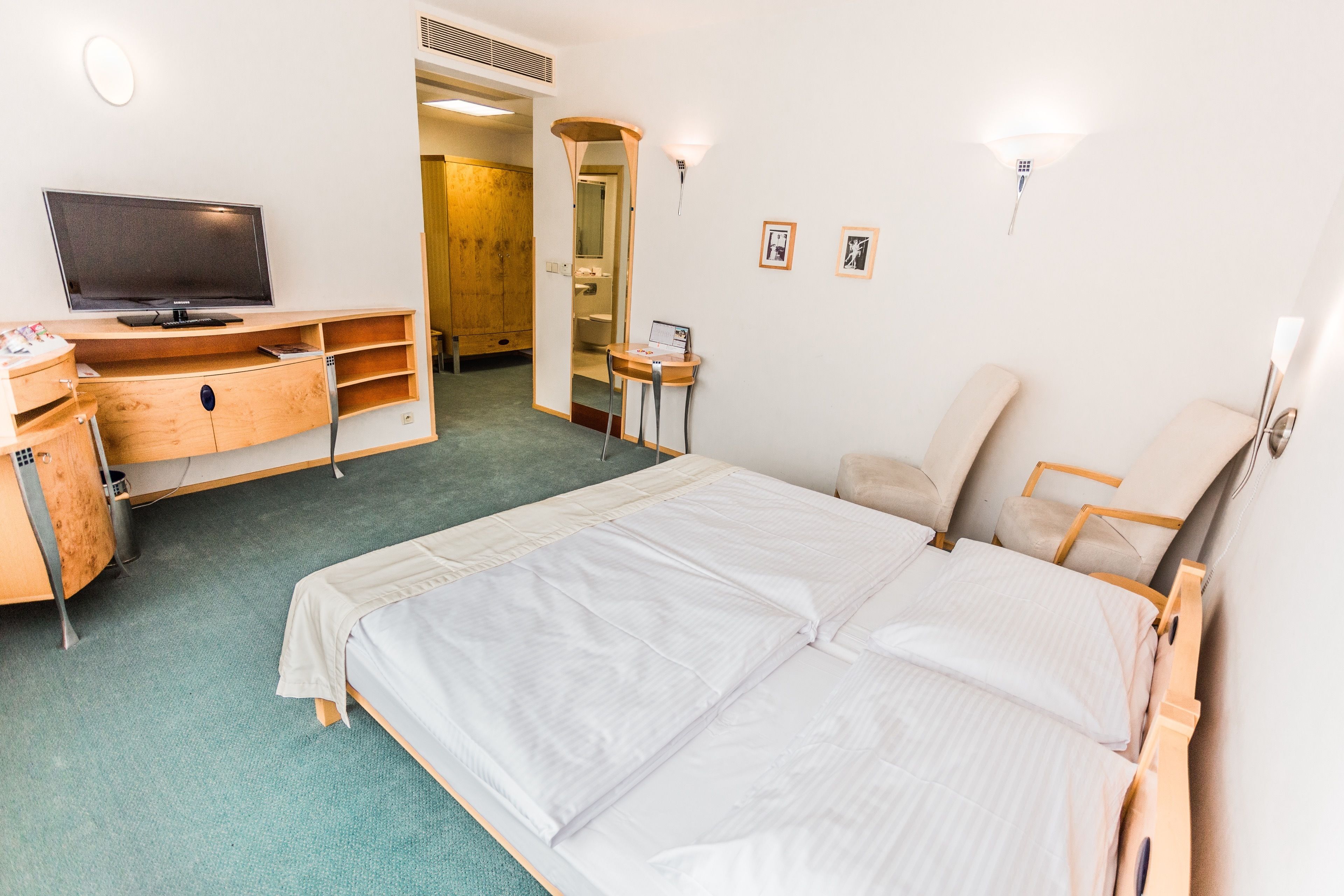 Une chambre d’hôtel comprenant un lit, un bureau avec une télévision, une petite table et une chaise.
