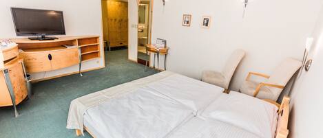 Une chambre d’hôtel comprenant un lit, un bureau avec une télévision, une petite table et une chaise.