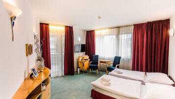 A hotel room with two beds, a desk, a chair, and a TV.