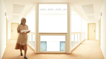 A spacious corridor with a high ceiling, large windows, and a view of the outdoors.