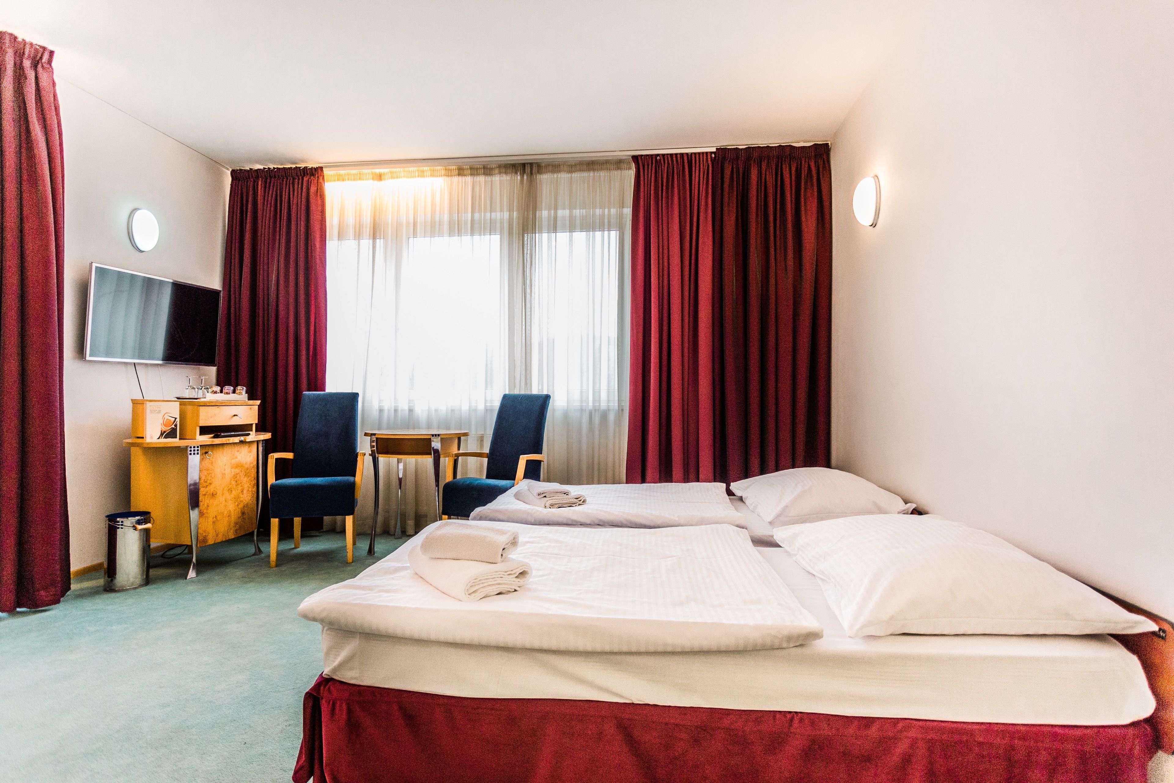 A hotel room with two beds, a desk with a computer, a chair, and a TV.