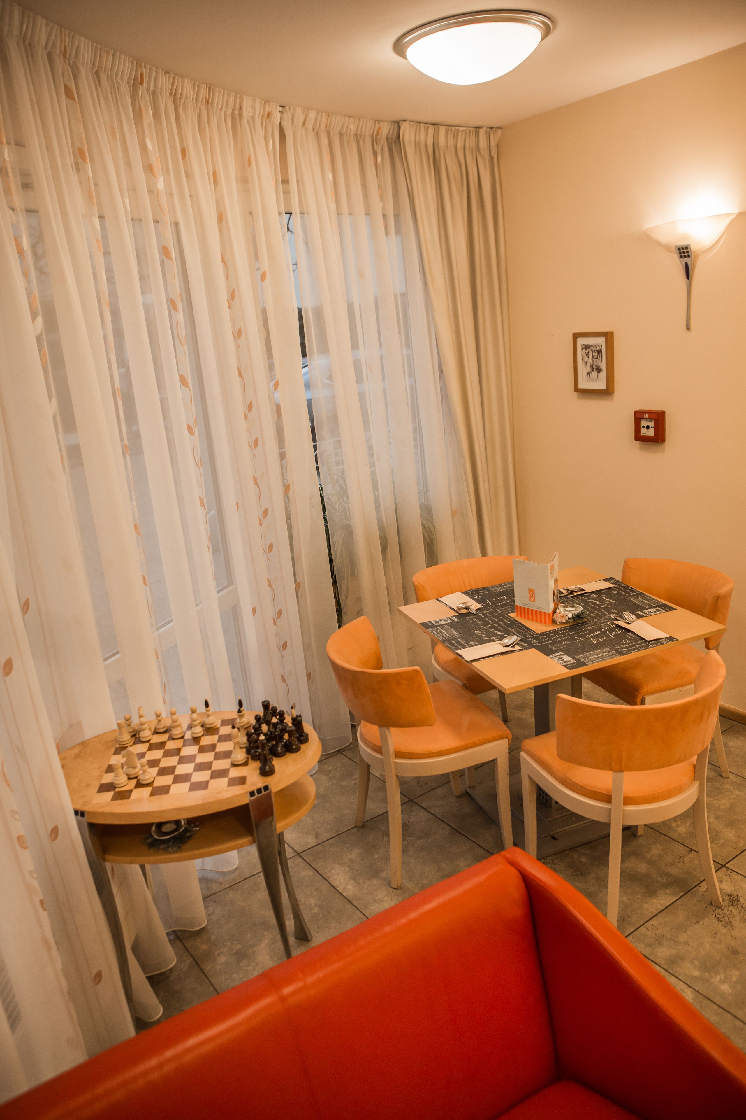 Un comedor con un tablero de ajedrez, sillas naranjas y una mesa.