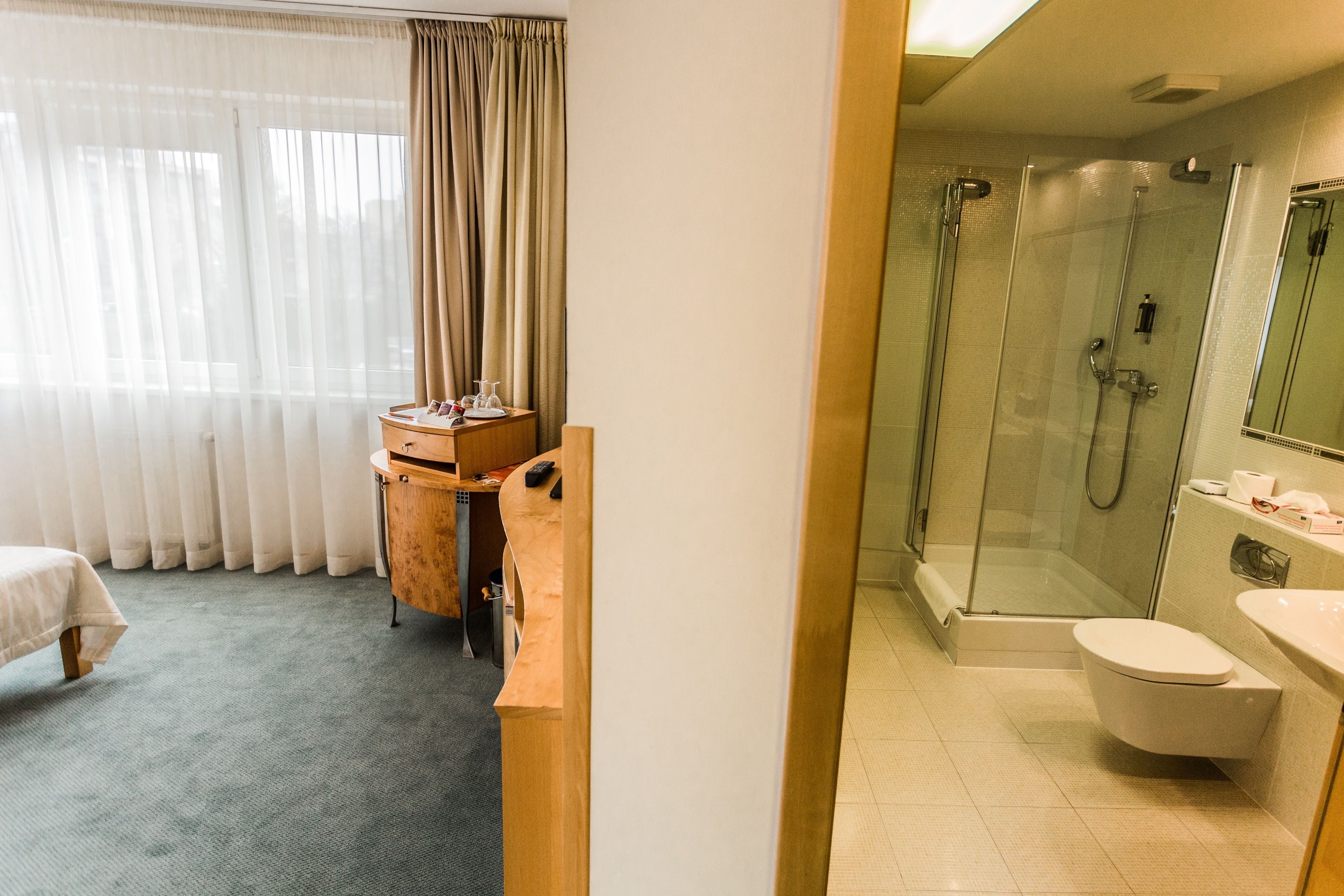 A hotel bathroom with a glass-enclosed shower, a toilet, and a sink.
