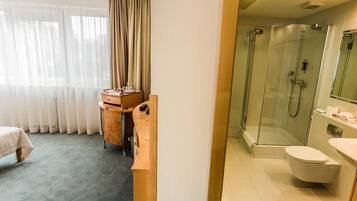 A hotel bathroom with a glass-enclosed shower, a toilet, and a sink.