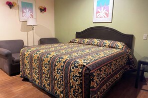 Une chambre d’hôtel avec un grand lit, une chaise, une lampe et deux œuvres d’art florales encadrées accrochées au mur.