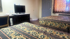 A hotel room with two beds, a desk, a television, and a patterned curtain. - Sun Star Inn Los Banos (Los Banos)