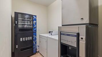 A laundry room with a vending machine, a washing machine, and an ice dispenser.