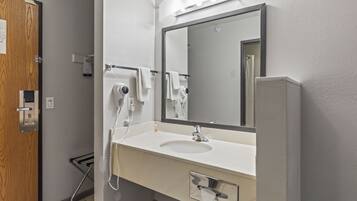 Un baño con lavamanos, espejo, toallero y secador de pelo.