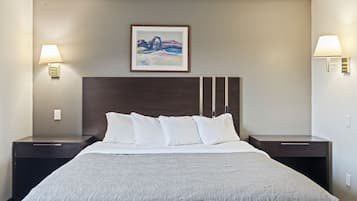 A hotel room with a large bed, two bedside tables, a headboard, and two wall-mounted lamps.