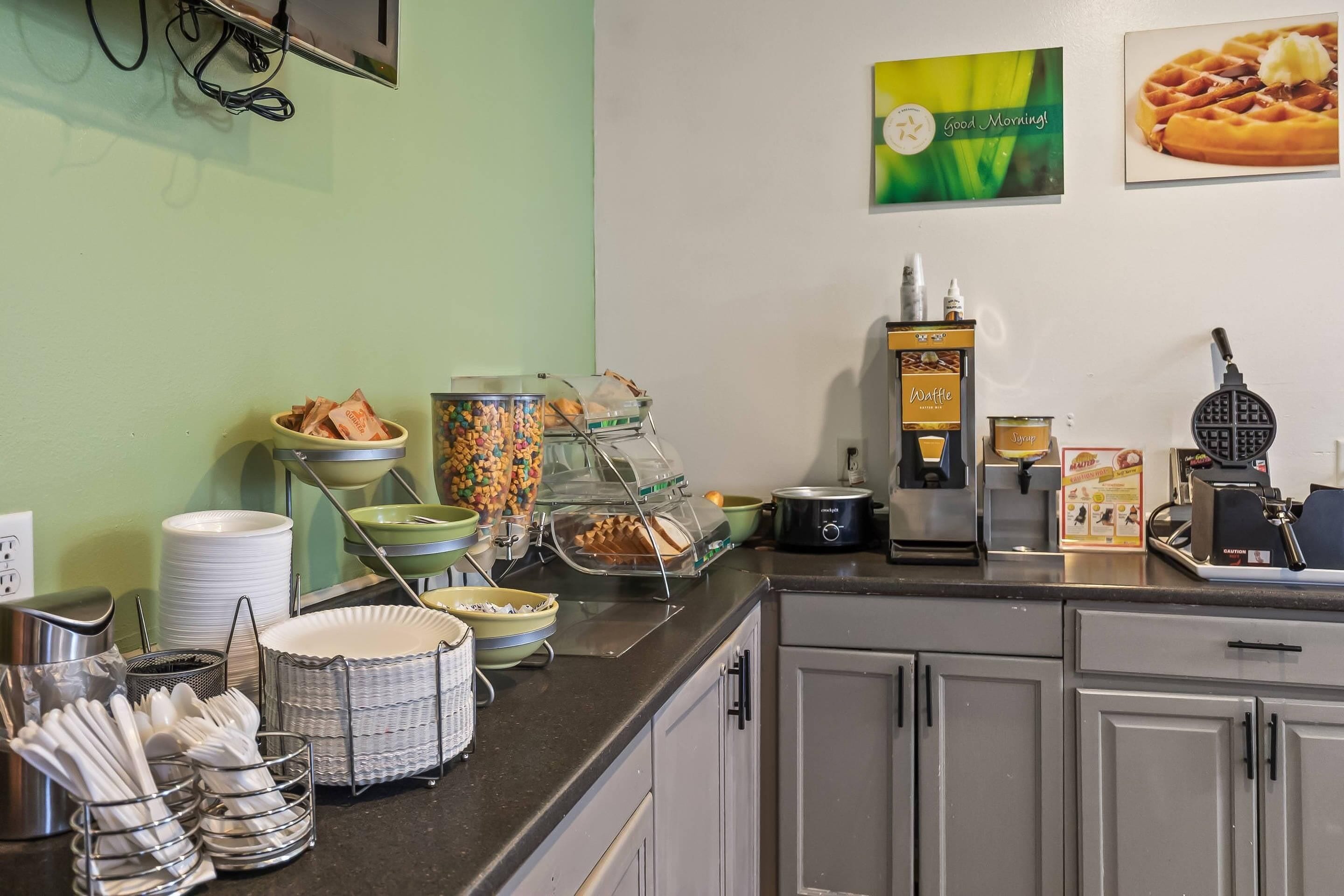 Un buffet de petit-déjeuner proposant une variété d’aliments et une machine à gaufres.