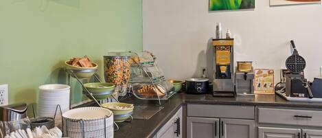 Un buffet de petit-déjeuner proposant une variété d’aliments et une machine à gaufres.